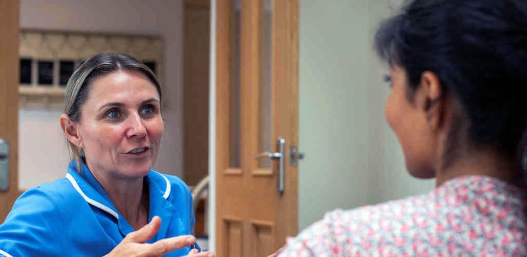 A nurse gives advice to a patient during a home visit.