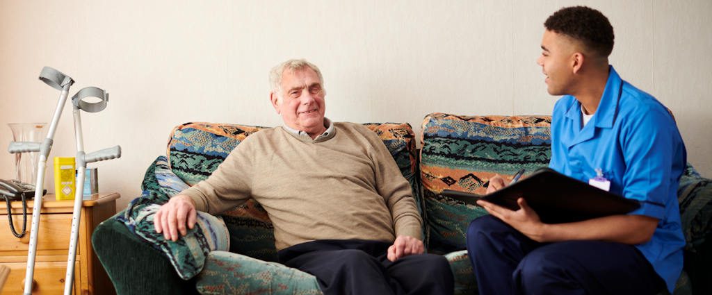 A patient and a healthcare worker talking on a sofa.