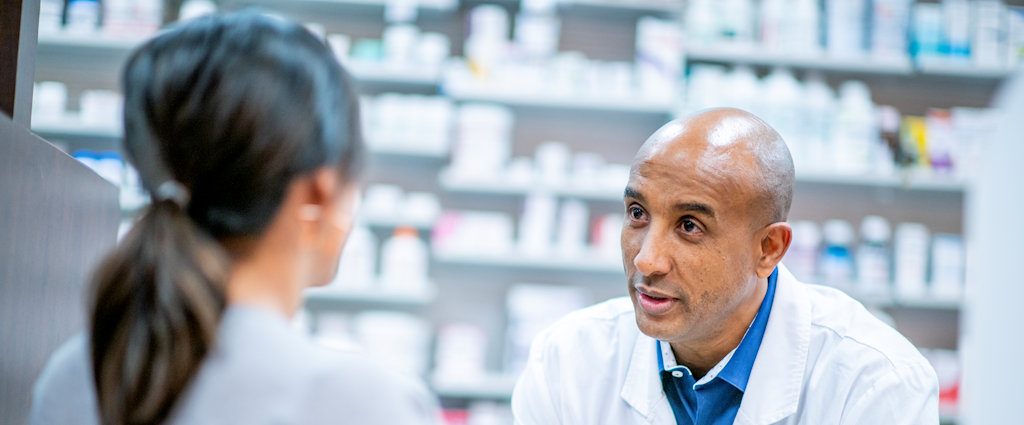 A pharmacist talking to a patient over the counter.