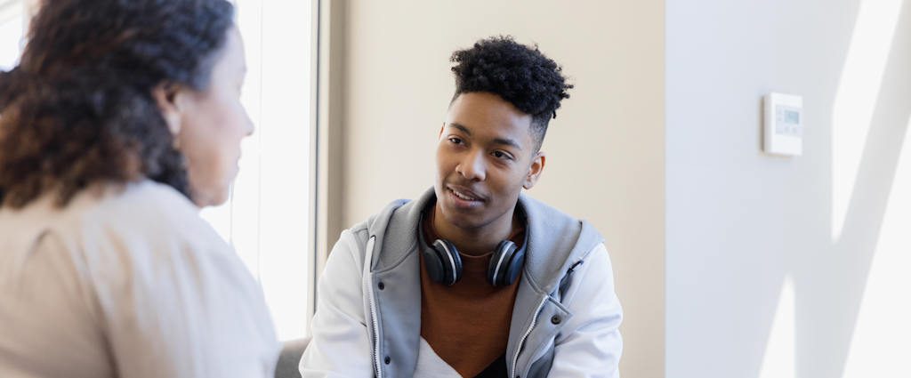 A young man listening to a woman talk.